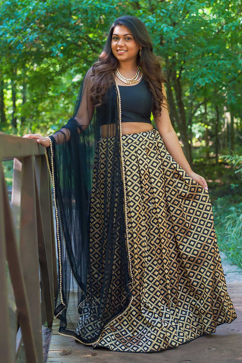 Chic two piece black lehenga, skirt covered in gold embroidered square design. Paired with black chiffon blouse. Finish this look by draping black dupatta with dainty gold trim on shoulders/shoulder.