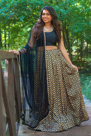 Chic two piece black lehenga, skirt covered in gold embroidered square design. Paired with black chiffon blouse. Finish this look by draping black dupatta with dainty gold trim on shoulders/shoulder.