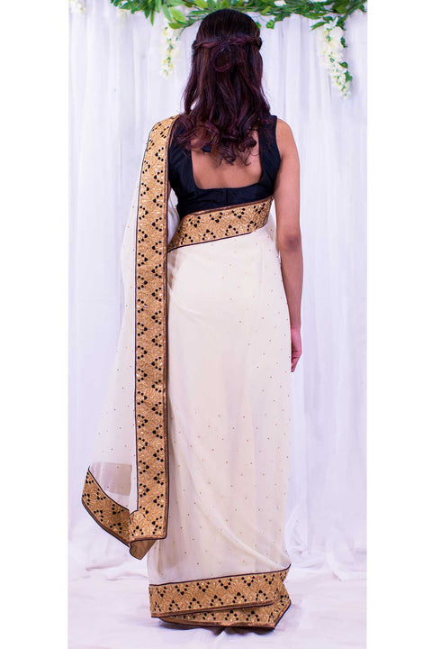 Angelic cream chiffon sari covered in gold specks, with heavy golden border designed with bindi appearing details.
