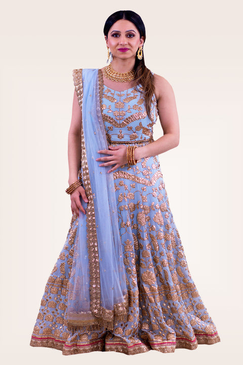 Iridescent light blue blouse with modern strap. Skirt with full of gold flower embroidery crafted from top to bottom with built in can can. Net dupatta with heavy border making it perfect for draping