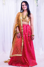 Lavish two piece lehenga with pink skirt, covered in gold stripes. Paired with gold blouse. Finish this look by draping matching net golden dupatta on shoulders/shoulder.