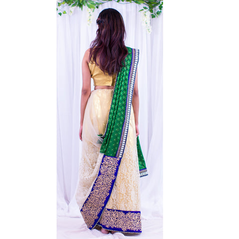Coy white net sari with intricate pattern at the bottom of skirt, with heavy dark blue border. Green pallu with full white flowers.