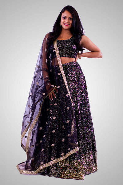 Stylish black lehenga completely covered in gold sequins on skirt and blouse. Finish this look by draping black net dupatta on shoulders/ shoulder.