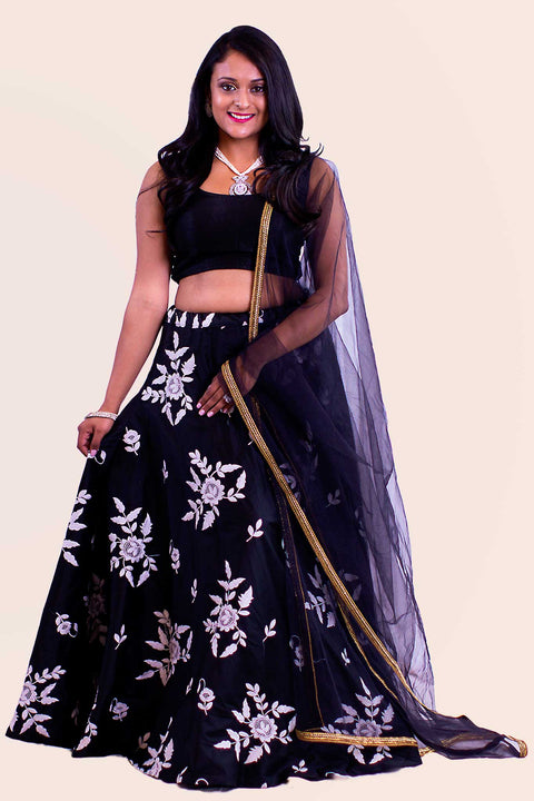 Deep black two piece lehenga with white flower thread embroidery skirt. Paired with black blouse. Finish this look by draping matching net dupatta on shoulders/ shoulder.