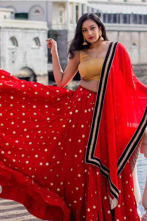 A Dreamy two piece red lehnga with golden snowflakes. Paired with black silk blouse. Drape matching black and red chiffon dupatta on shoulders/ shoulder to finish this look.