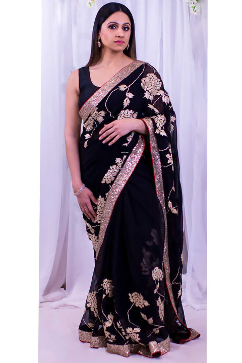 Majestic black chiffon sari with heavy gold border with dainty red trim.