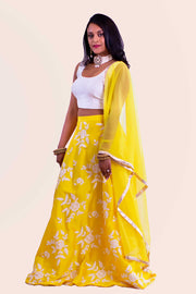 Coy two piece yellow lehenga with luscious white flowers threaded on skirt. Paired with simple modern blouse. Finish this look with yellow chiffon dupatta decorated with gold trim on shoulders/ shoulder. 