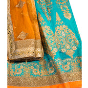 Breathe taking tropical lehenga, skirt consisting of true toned teal and orange gold border. Decadent gold embroidery on skirt and long sleeved blouse for refined appeal. Finish this look by draping heavy chiffon color blocking dupatta, thick gold border on shoulders/ shoulder.