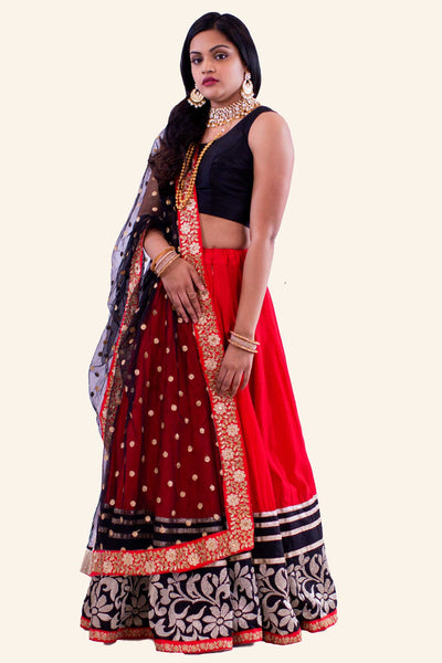 Red two piece lehenga with black blouse. Red skirt with heavy flower gold embroidery with golden glitter trim. Finish this look by draping matching red and black border dupatta on shoulders/ shoulder.