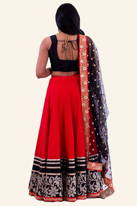 Red two piece lehenga with black blouse. Red skirt with heavy flower gold embroidery with golden glitter trim. Finish this look by draping matching red and black border dupatta on shoulders/ shoulder.